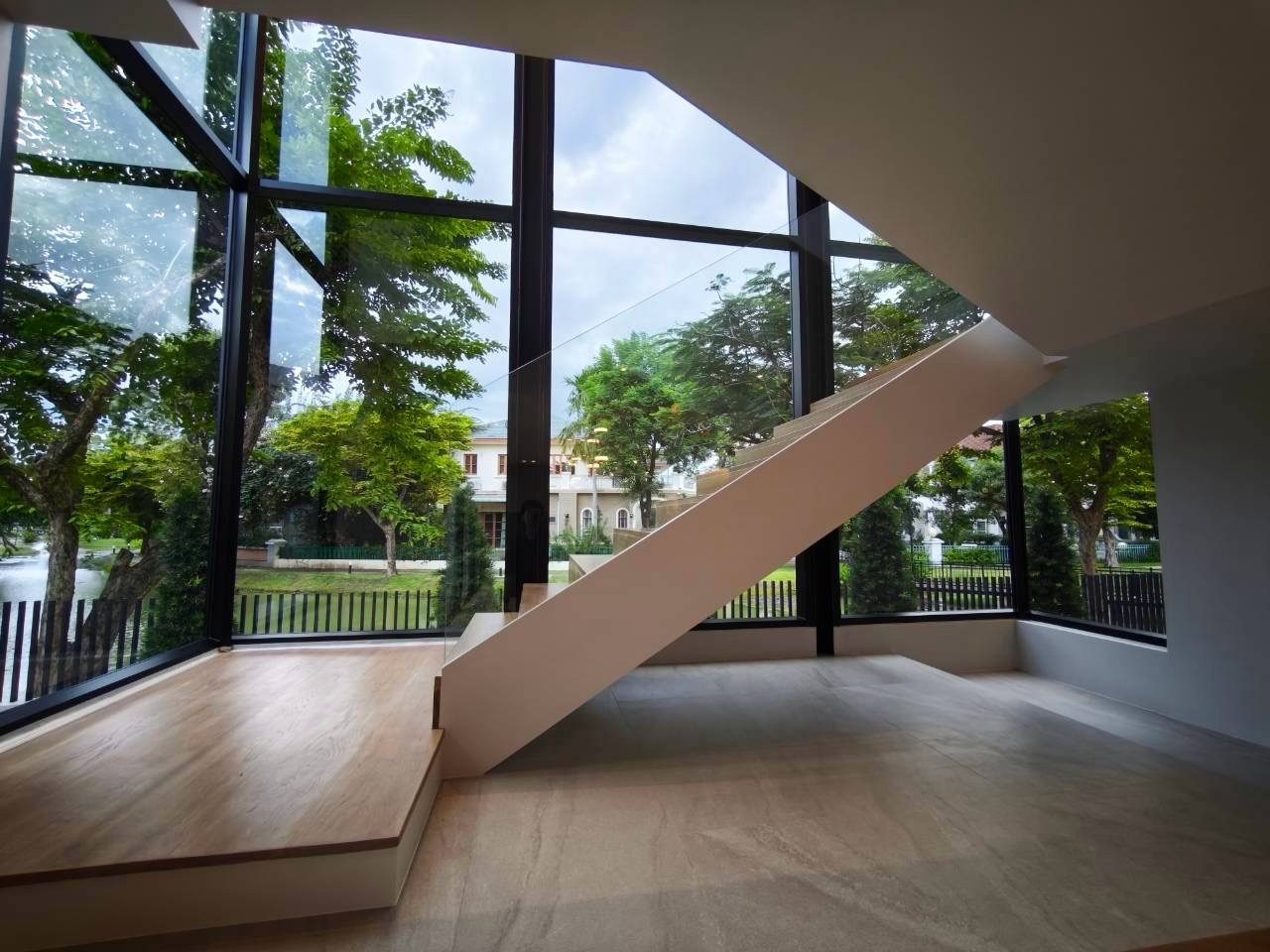 A stair hall with a floor-to-ceiling glass corner in black Aluk SL50 frames, a floating stair and the garden beyond