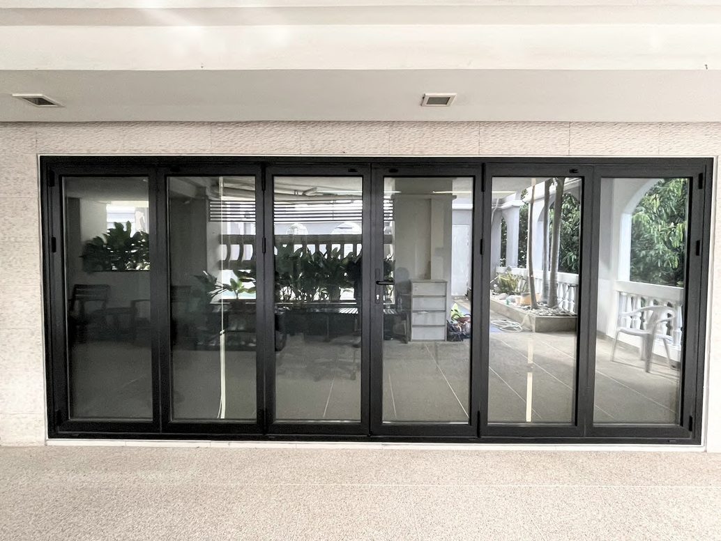 A six-panel black VBM FD-95 bi-folding door, closed, across the terrace wall of an office in Chatuchak, Bangkok