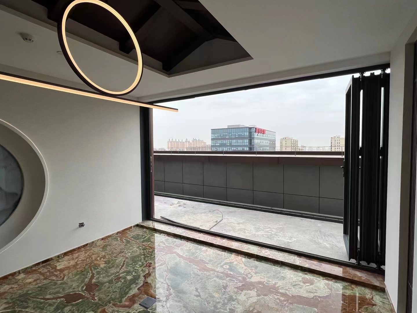 A VBM FD-95 bi-folding door folded fully to one side, opening a marble-floored room to a roof terrace