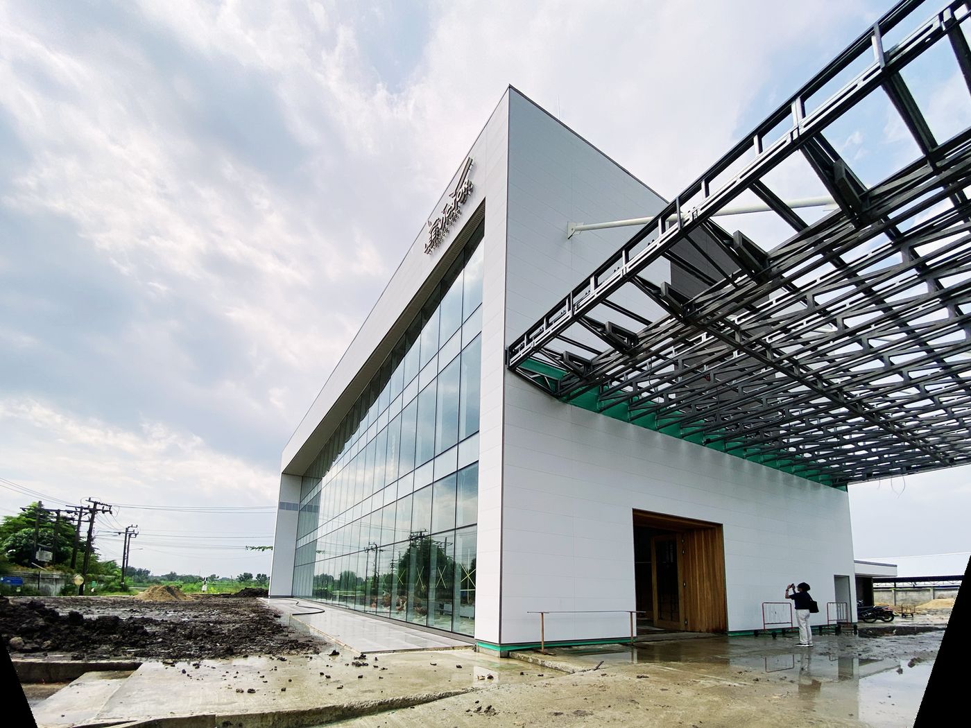 A three-storey white showroom with glass walls and a cantilevered steel-framed roof