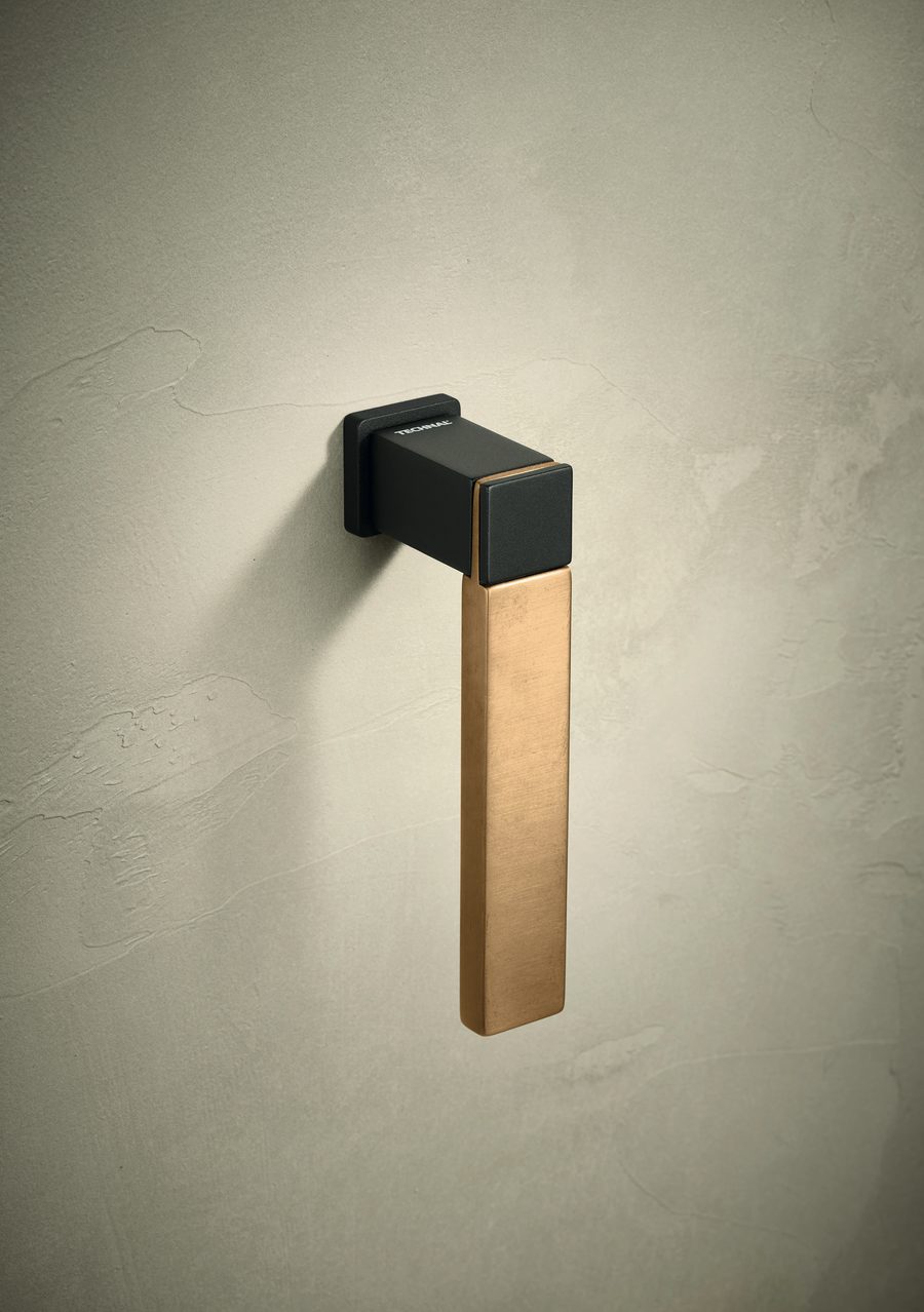 A Technal PASSION handle with a black square head and a bronze-toned lever, on a cream plaster wall