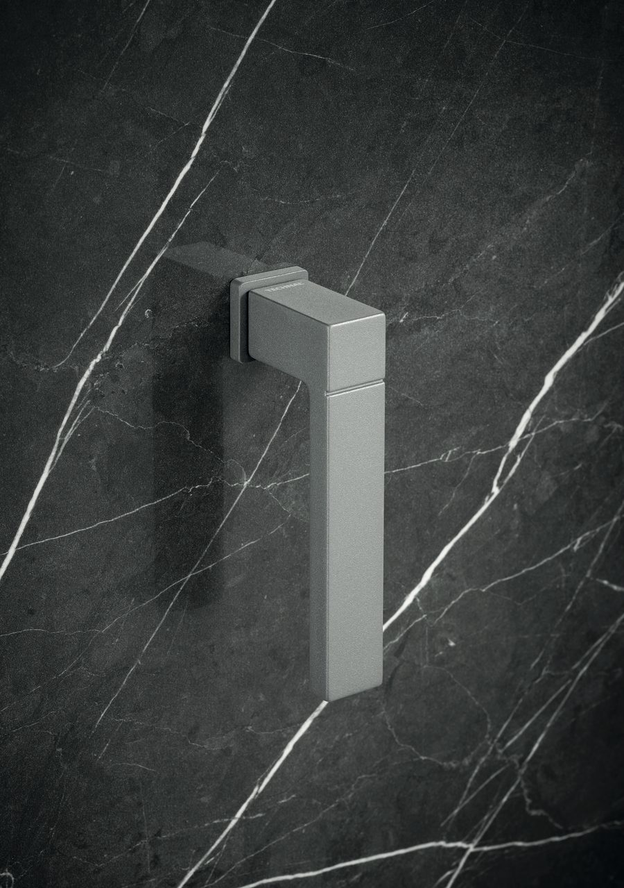 A Technal SELECTION square window handle in a grey metallic finish against dark veined marble